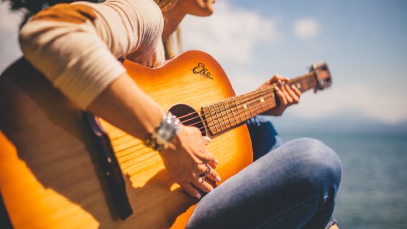 Woman Sitting Holding Acoustic Guitar